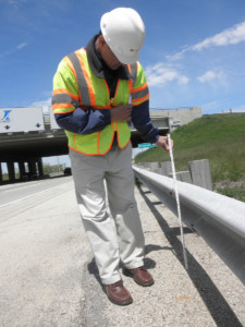 Highway construction inspector measuring a guard rail