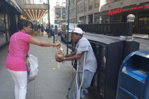 Woman giving food to homeless man
